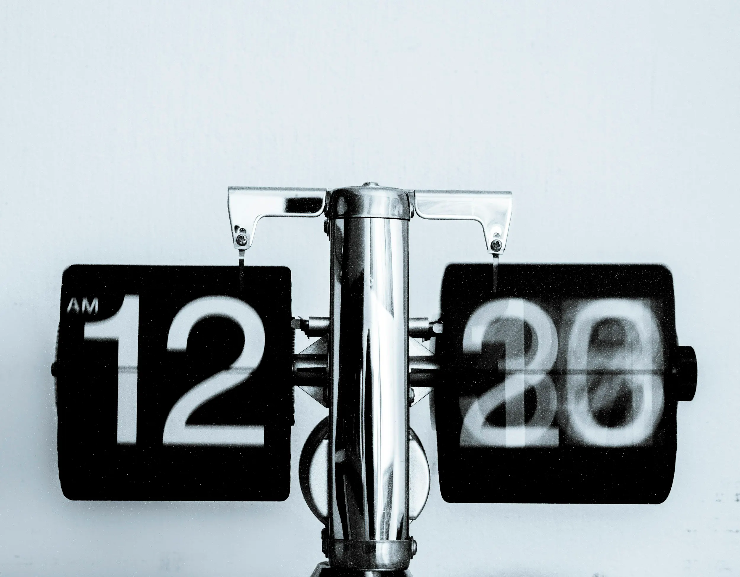 A retro-style flip clock showing 12:20 AM in motion blur, evoking a sense of time passing.